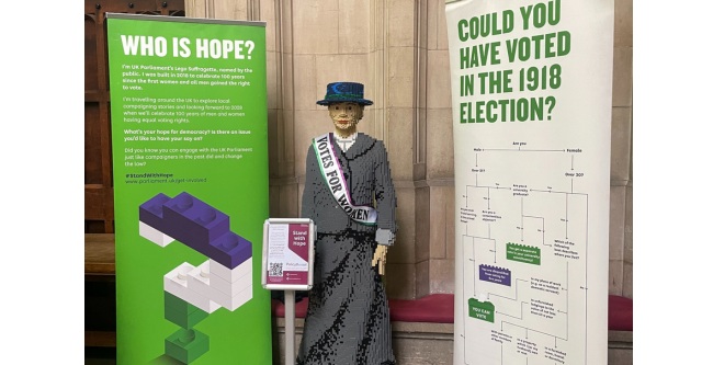A lego model of Hope, a suffragette, alongside information about the model and the suffrage movement